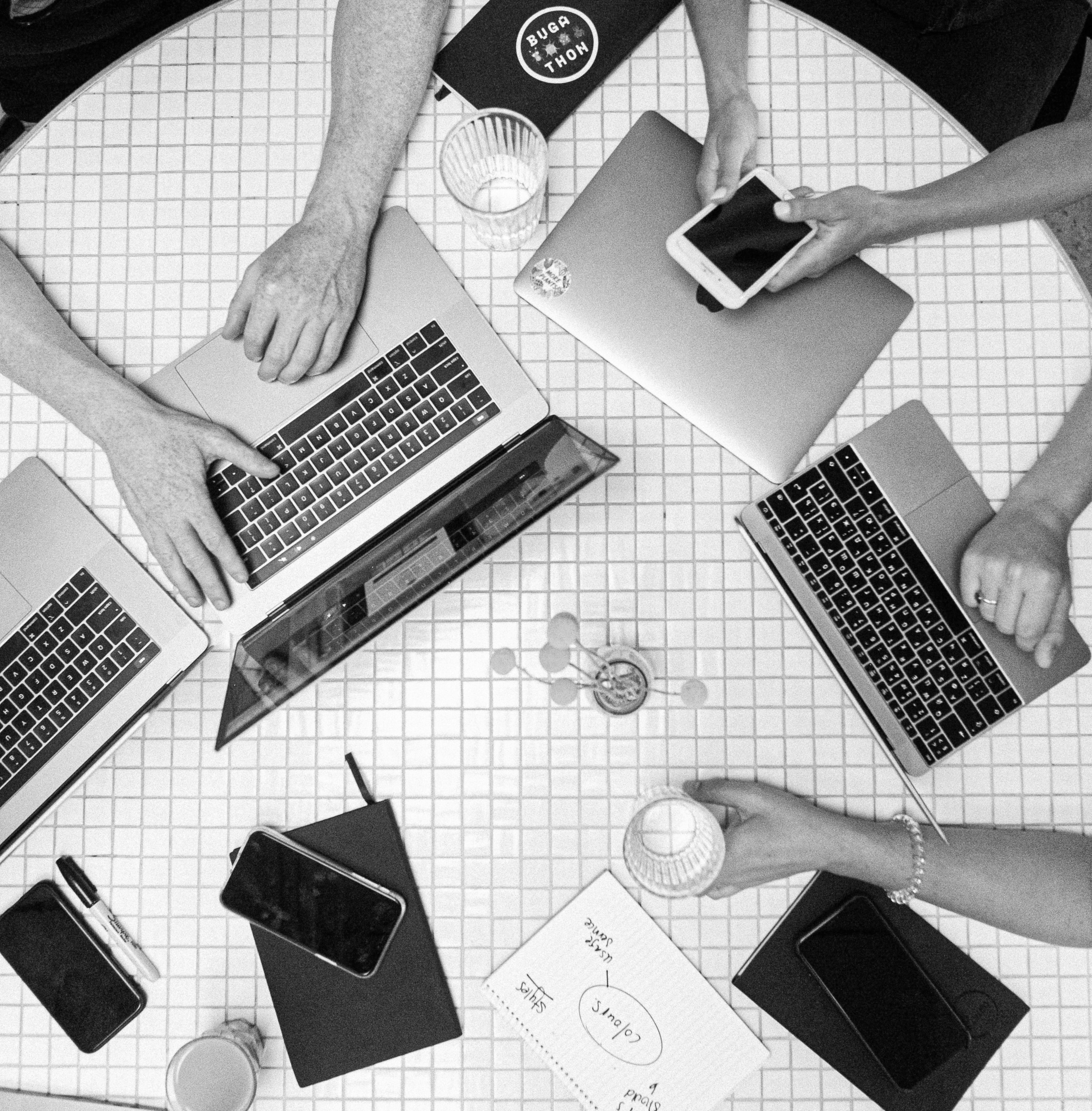 Mesa de trabajo de Macbooks y personas reunidas